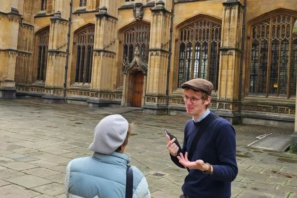 Rory, the tour guide, explains the history of the Divnity School, Oxford, to a visitor.